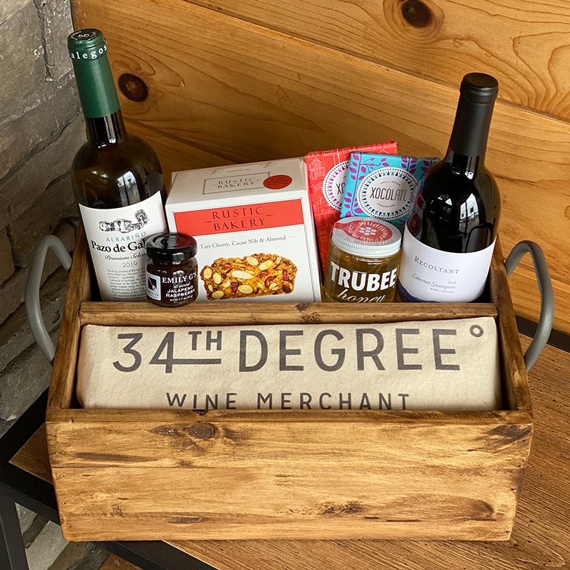 a gift basket from 34th Degree Wine Merchant, featuring wine, crackers, spreads, and chocolate