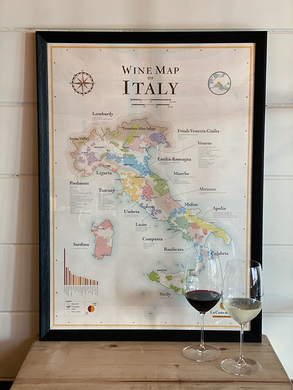 a wine map of Italy poster on a table with two glasses of wine in front of it